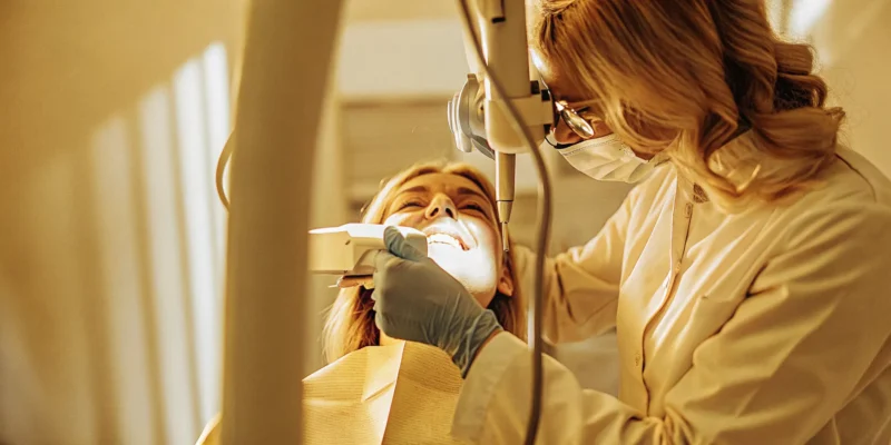 Dentist gently examining patient's gums in a modern San Diego dental office